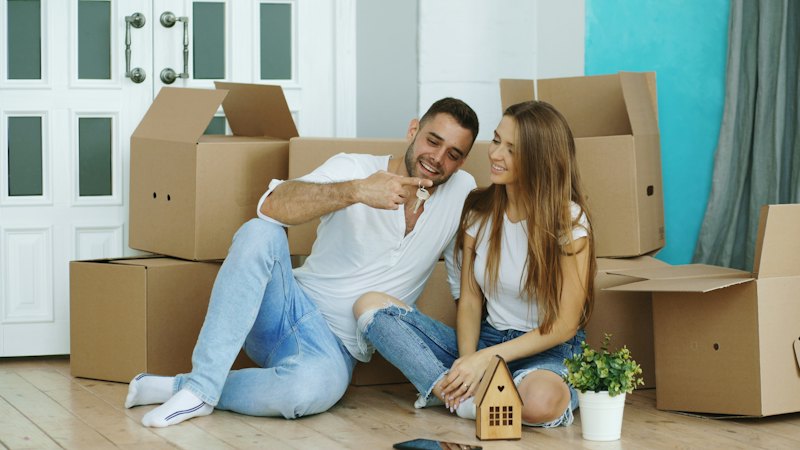 A couple surrounded by moving boxes in their new home
